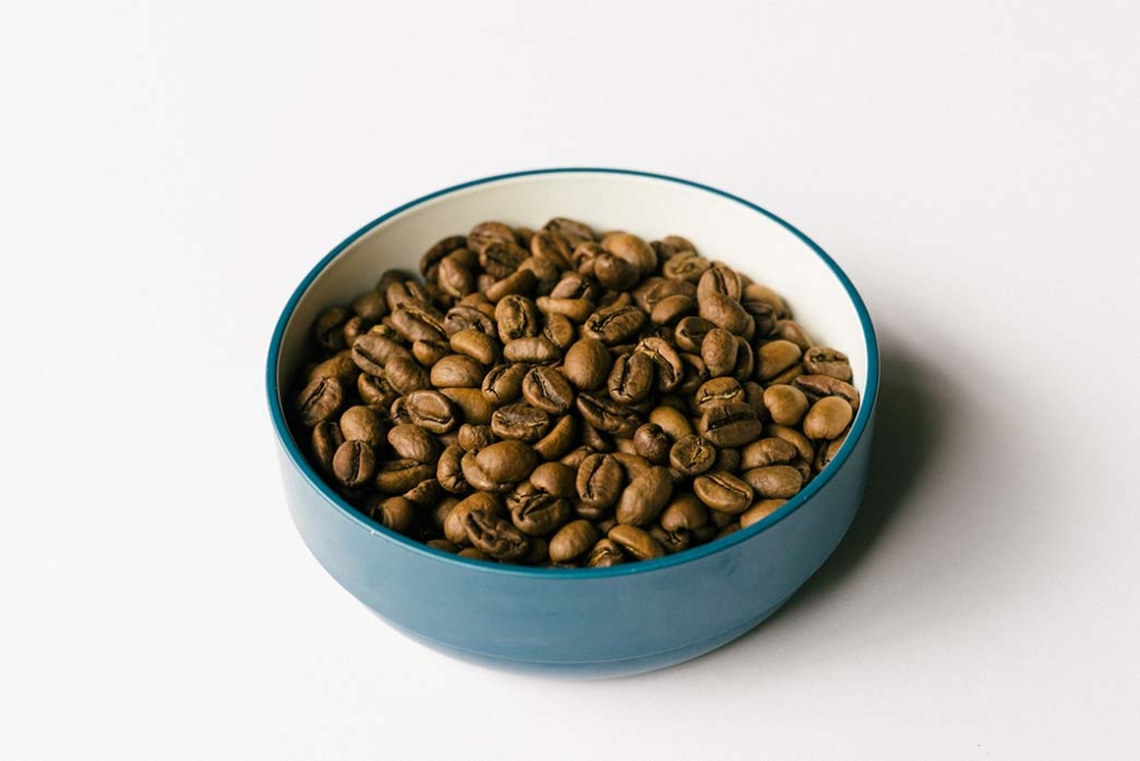 青い丸皿にコーヒー豆が載せられている画像